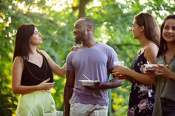 Image showing Happy friends eating and drinking beers at barbecue dinner on sunset time