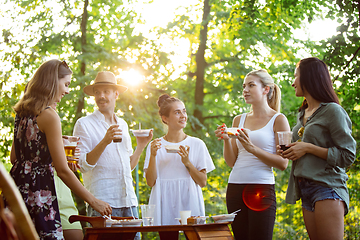 Image showing Happy friends eating and drinking beers at barbecue dinner on sunset time