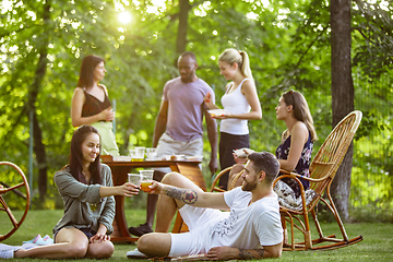 Image showing Happy friends eating and drinking beers at barbecue dinner on sunset time