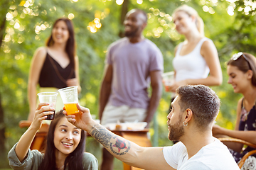 Image showing Happy friends eating and drinking beers at barbecue dinner on sunset time