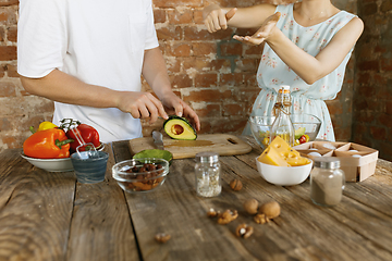 Image showing Young caucasian couple cooking together against brick wall