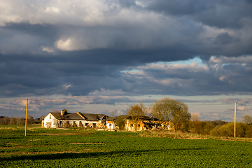 Image showing Landscape with cereal field, old farm house and blue sky.