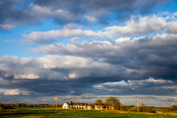 Image showing Landscape with cereal field, old farm house and blue sky.