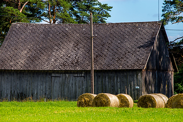 Image showing Hay bales in the meadow near the barn.