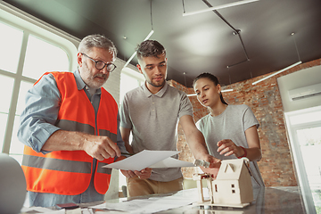 Image showing Foreman or achitect shows house, office or store design plans to a young couple