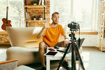 Image showing Caucasian male blogger with camera recording video review of gadgets at home