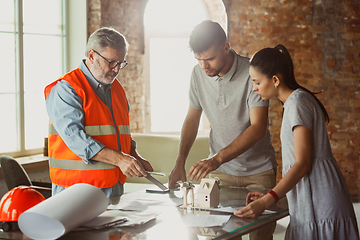 Image showing Foreman or achitect shows house, office or store design plans to a young couple