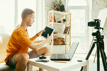 Image showing Caucasian male blogger with camera recording video review of gadgets at home