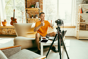 Image showing Caucasian male blogger with camera recording video review of gadgets at home