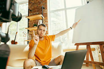 Image showing Caucasian male blogger with camera recording video review of gadgets at home