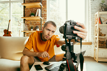 Image showing Caucasian male blogger with camera recording video review of gadgets at home