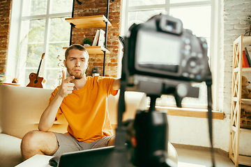 Image showing Caucasian male blogger with camera recording video review of gadgets at home