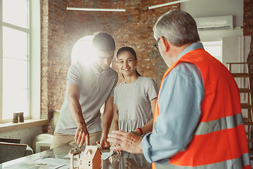 Image showing Foreman or achitect shows house, office or store design plans to a young couple