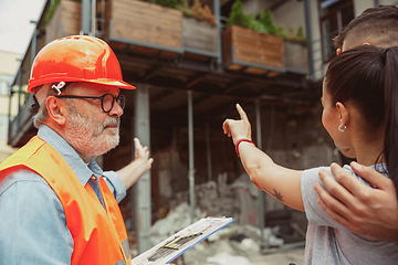 Image showing Foreman or achitect shows house, office or store design plans to a young couple