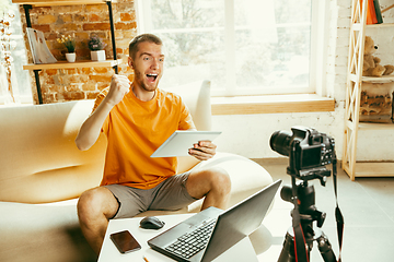 Image showing Caucasian male blogger with camera recording video review of gadgets at home