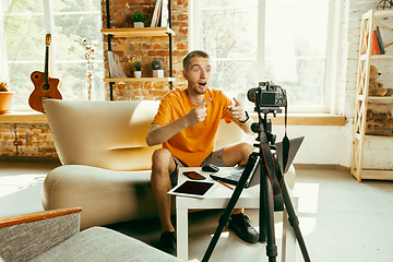 Image showing Caucasian male blogger with camera recording video review of gadgets at home