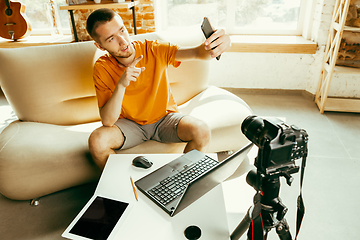 Image showing Caucasian male blogger with camera recording video review of gadgets at home