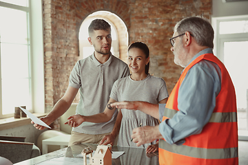 Image showing Foreman or achitect shows house, office or store design plans to a young couple