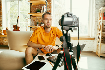 Image showing Caucasian male blogger with camera recording video review of gadgets at home