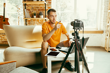 Image showing Caucasian male blogger with camera recording video review of gadgets at home