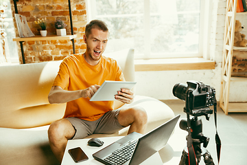 Image showing Caucasian male blogger with camera recording video review of gadgets at home