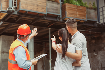 Image showing Foreman or achitect shows house, office or store design plans to a young couple