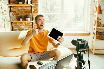 Image showing Caucasian male blogger with camera recording video review of gadgets at home