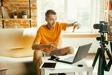 Image showing Caucasian male blogger with camera recording video review of gadgets at home