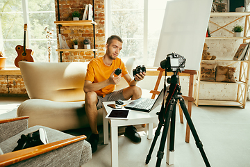 Image showing Caucasian male blogger with camera recording video review of gadgets at home