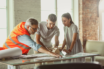 Image showing Foreman or achitect shows house, office or store design plans to a young couple