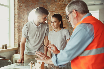 Image showing Foreman or achitect shows house, office or store design plans to a young couple