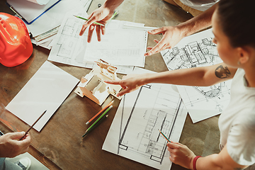 Image showing Foreman or achitect shows house, office or store design plans to a young couple