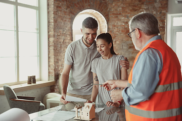 Image showing Foreman or achitect shows house, office or store design plans to a young couple