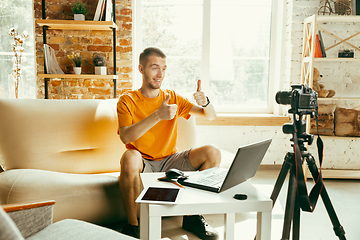 Image showing Caucasian male blogger with camera recording video review of gadgets at home