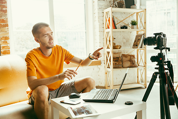 Image showing Caucasian male blogger with camera recording video review of gadgets at home