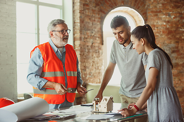 Image showing Foreman or achitect shows house, office or store design plans to a young couple