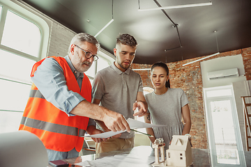 Image showing Foreman or achitect shows house, office or store design plans to a young couple