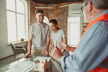 Image showing Foreman or achitect shows house, office or store design plans to a young couple