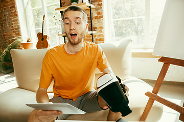 Image showing Caucasian male blogger with camera recording video review of gadgets at home