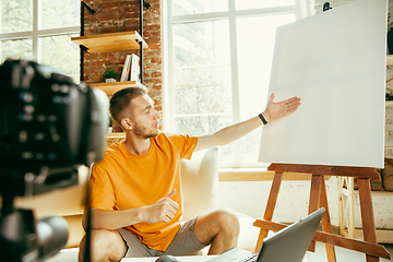 Image showing Caucasian male blogger with camera recording video review of gadgets at home