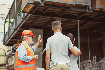 Image showing Foreman or achitect shows house, office or store design plans to a young couple