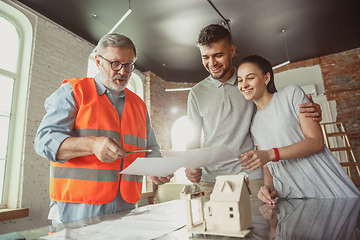 Image showing Foreman or achitect shows house, office or store design plans to a young couple