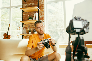 Image showing Caucasian male blogger with camera recording video review of gadgets at home