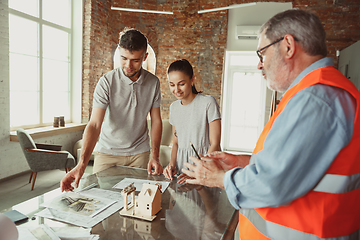 Image showing Foreman or achitect shows house, office or store design plans to a young couple