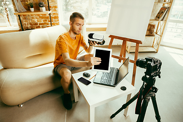 Image showing Caucasian male blogger with camera recording video review of gadgets at home