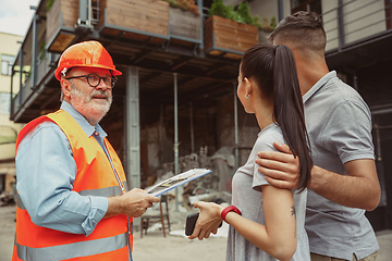 Image showing Foreman or achitect shows house, office or store design plans to a young couple