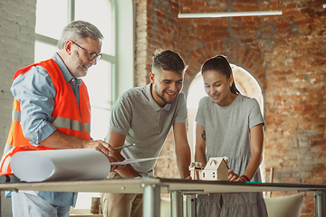 Image showing Foreman or achitect shows house, office or store design plans to a young couple