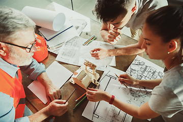 Image showing Foreman or achitect shows house, office or store design plans to a young couple