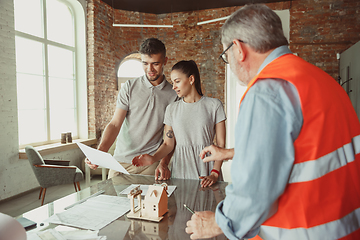 Image showing Foreman or achitect shows house, office or store design plans to a young couple