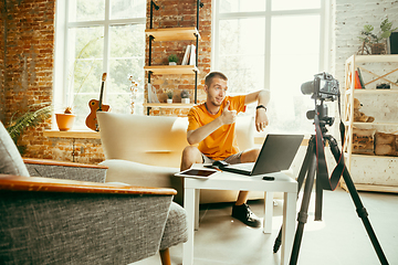 Image showing Caucasian male blogger with camera recording video review of gadgets at home